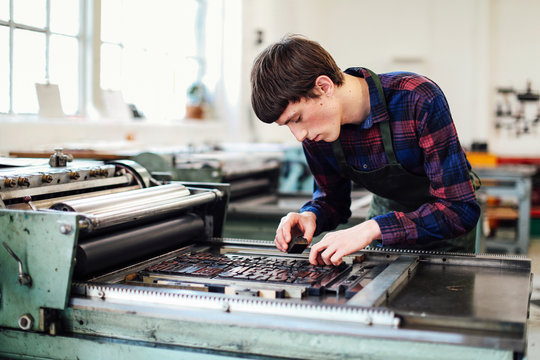 Young man working with printing machine