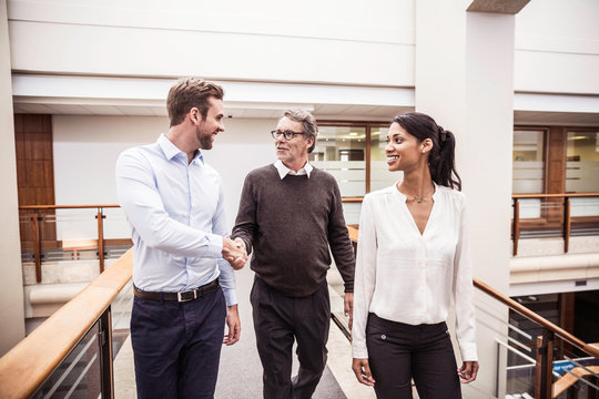 Senior businessman shaking hands with client on office walkway