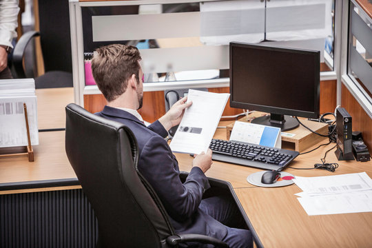 Businessman reading paperwork at office desk