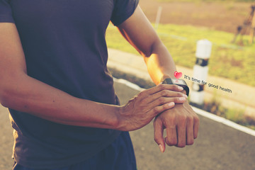 Handsome young sportsman stand and using smart watch outdoors