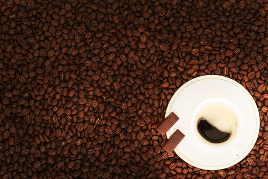 Cup of coffee with chocolate pieces on coffee beans background. © GLandStudio