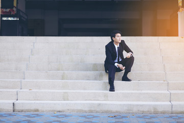 Portrait of smiling young handsome businessman sitting on the stairs