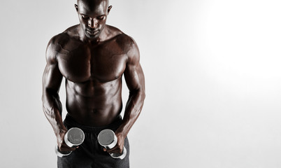 Fototapeta na wymiar Muscular african man exercising with dumbbells