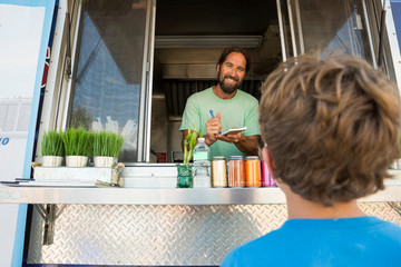 Man in fast food trailer serving young boy through hatch