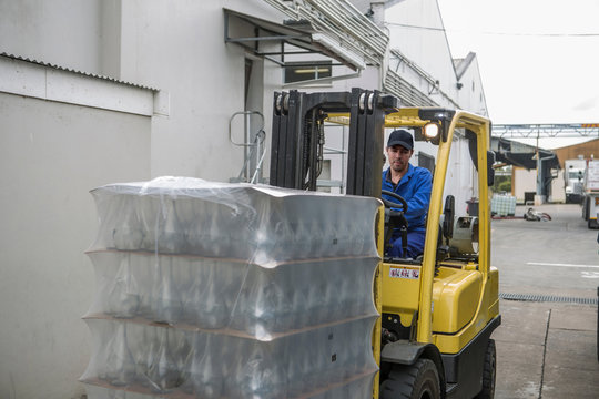 Forklift driver loading pallets at packaging factory