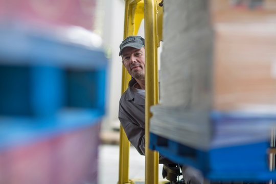 Forklift driver loading pallet onto truck at packaging factory