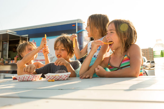 Group of children eating fast food beside fast food trailer