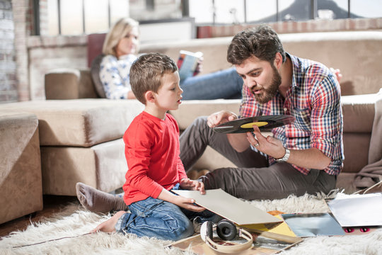 Father showing vinyl record to son at home