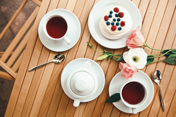 Traditional dessert Pavlova cake with fresh berries and tea