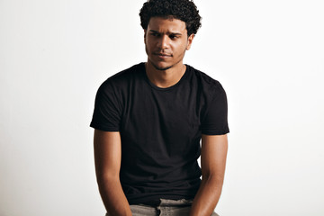 Ironic thoughtful handsome young man with an afro wearing a black sleeveless cotton t-shirt against...