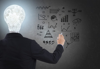 businessman with lighbulb in head standing and hand drawing inspiration or idea, brainstorming on blackboard background.