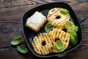 Grill pan with barbecued pineapple slices and honey