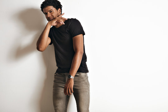 Dancing smiling relaxed black young model in an unlabeled black t-shirt and skinny grey jeans isolated on white