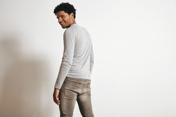 Back view of attractive latino man looking with happy smile in camera turning around, isolated on white, wearing blank heather grey clothing