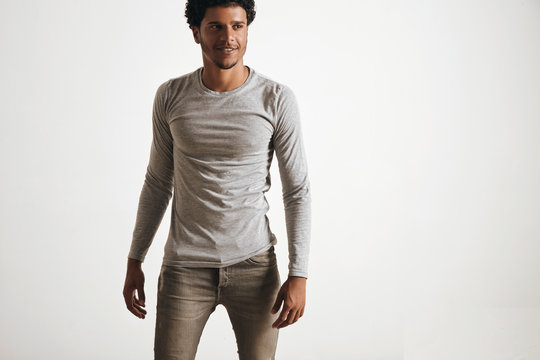 Sexy fitted latino male walking wears blank unlabeled grey logsleeve and stressed jeans, isolated on white