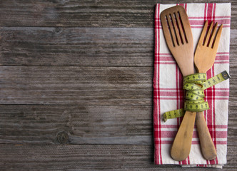 Cubiertos de madera con una cinta metrica (concepto de dieta y comida sana)