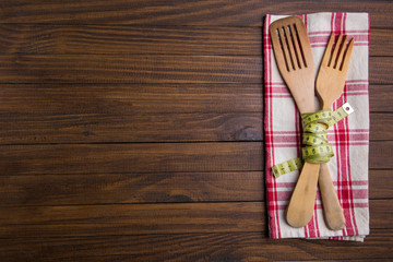 Cubiertos de madera con una cinta metrica (concepto de dieta y comida sana)