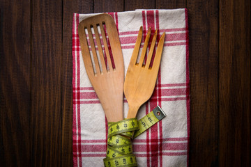 Cubiertos de madera con una cinta metrica (concepto de dieta y comida sana)