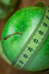 Manzana verde con cinta sobre fondo blanco (salud y concepto de dieta) 
