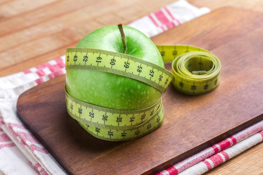 Manzana verde con cinta sobre una mesa de madera rustica (salud y concepto de dieta) 