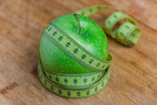 Manzana verde con cinta sobre fondo blanco (salud y concepto de dieta) 