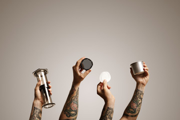 Four shots of hands holding various aeropress parts combined in one image with off white background Alternative coffee brewing commercial