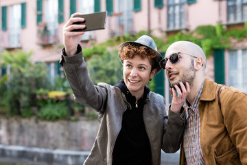 Couple of friends outdoor in the city taking selfie with smart phone hand hold outdoor in the city, smiling - vanity, social network, communication concept