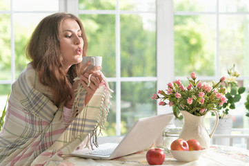 young woman with laptop and tea