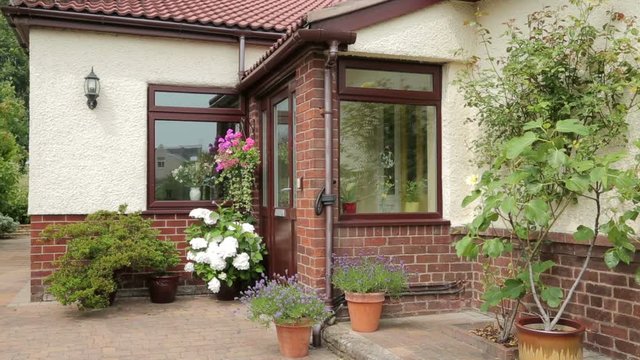 Front door and porch of bungalow with pots and shrubs