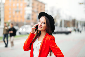 young Woman in black hat using mobile phone on city street..