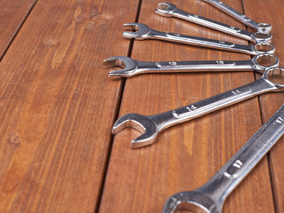 Set of wrenchs chrome metal spanner instruments on wooden surface