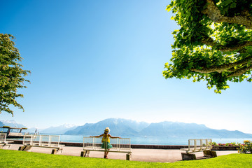 Beautiful landscape view on the park and mountains near Geneva lake with woman sitting on the bench in Switzerland
