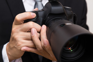 Business man with dslr camera in black suit close up