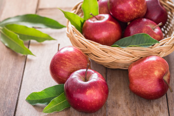 Red apples on wooden table and basket