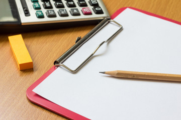 Paper on red file with calculator, pencil and orange note
