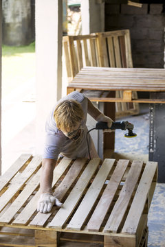 Man sanding pallet with a random orbital sander