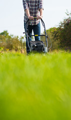 Young man mowing the grass