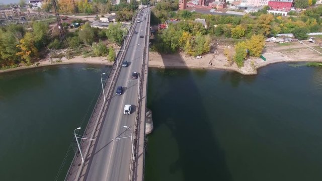 Flying over the bridge at Samara river with river cranes at background . Car traffic at bridge.  Drone moving forward. 4K Aerial stock footage clip.
