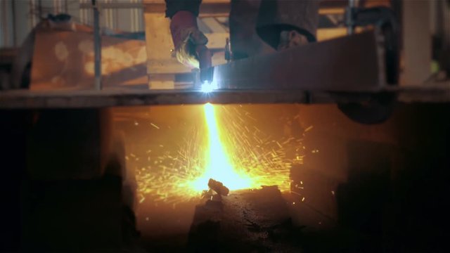 Welder in factory welding metal in modern stock workshop