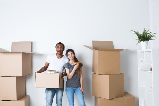 Smiling couple unpack boxes in new home.