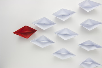 Red paper ship leading white ones, leadership concept