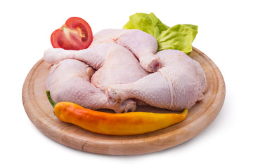 Fresh raw chicken legs arrangement on kitchen cutting board with lettuce, tomato and pepper