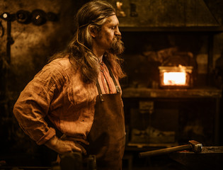 Naklejka premium Senior blacksmith in smithy