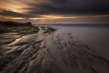 Beautiful sunset decorated with waves and mosses stone