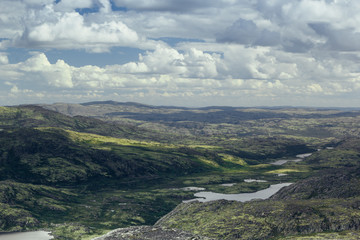 Highlands valley with views of the lake and the green hills in sunny cloudy day. Arctic summer, the tundra, Norway.