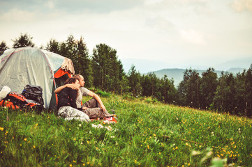 loving couple sitting beside a tent in the mountains