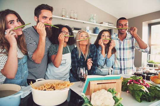 Silly adults sniffing asparagus stalks in kitchen