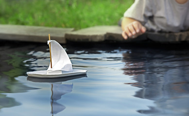 White toy boat at a pier in a pond in summer