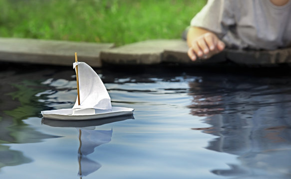 White toy boat at a pier in a pond in summer