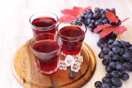 Glasses of grape juice with ice and black grapes